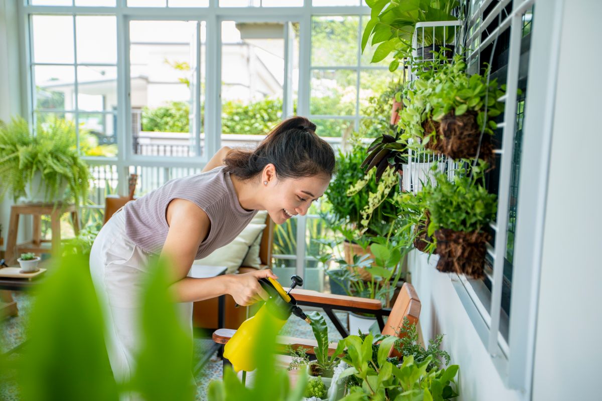 femeie care isi stropeste plantele din balcon&nbsp;